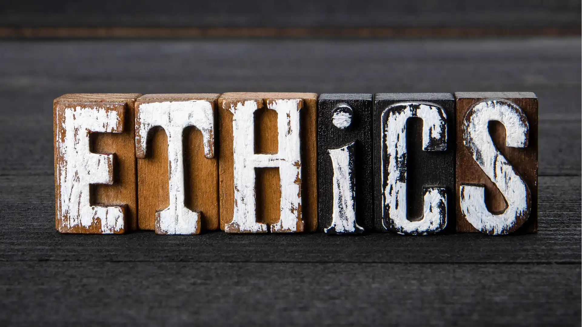 Wooden blocks spelling the word 'ETHICS' on a dark surface.